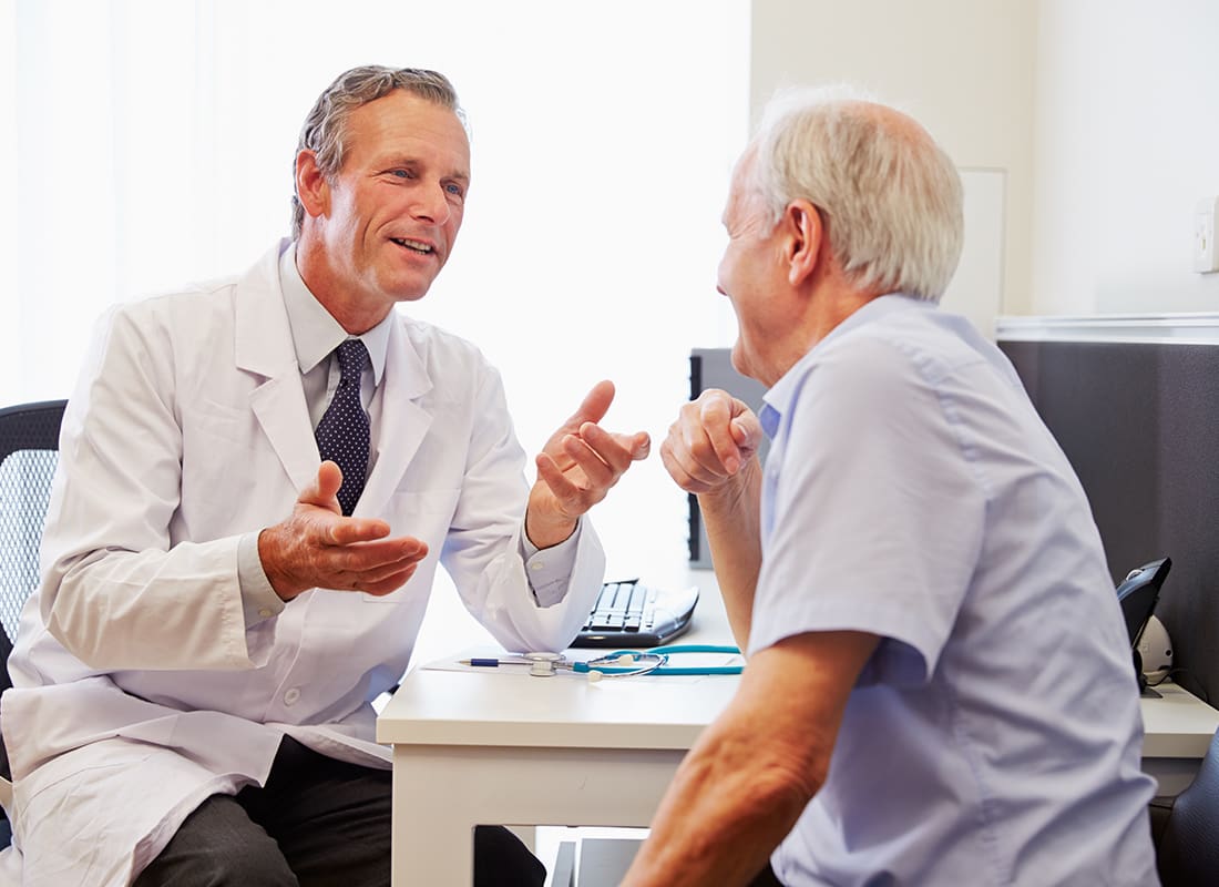 Employee Benefits - Doctor Speaking With a Patient in His Office